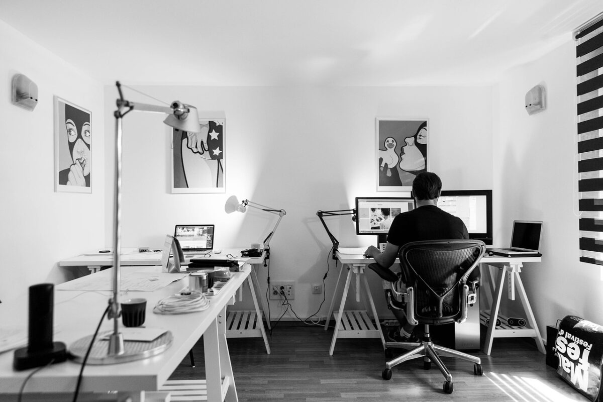 A man sits at his desk in the small office of a creative business.